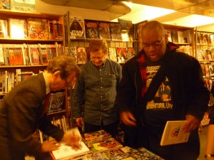 Batton signing for a fan; that's Rich Watson with the Supernatural Law T-shirt.